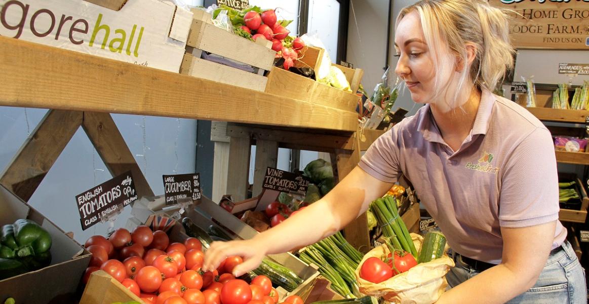 Fresh and Fruity trader putting vegetables into a bag Fresh and Fruity trader putting vegetables into a bag