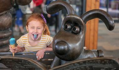 Child having selfie with Wallace and Gromit Statue