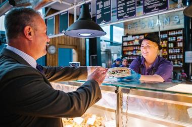 Trader serving customer a sandwich 