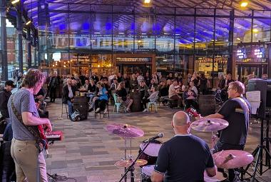 Band playing to crowd under the canopy outside The Orchard