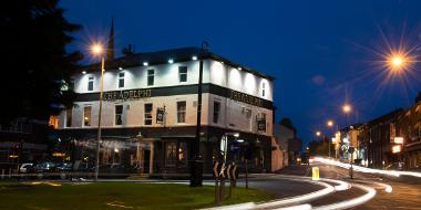 Outside the Adelphi at night with time-lapse of traffic passing by.