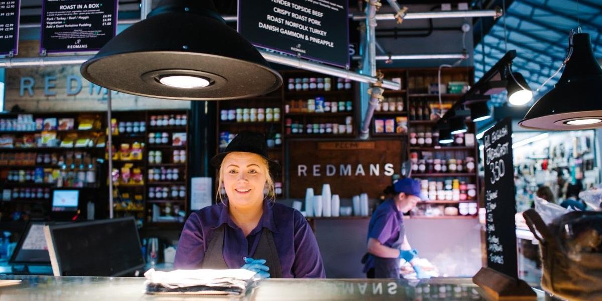 Trader behind counter at Redman's, in Preston Market Hall